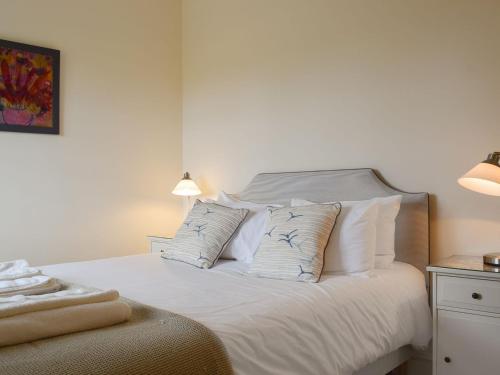 um quarto com uma cama com lençóis brancos e almofadas em Alice Cottage em Thurning