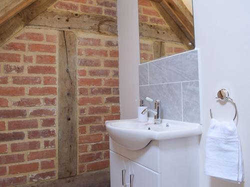 a bathroom with a sink and a brick wall at Woltons Mill in Much Marcle