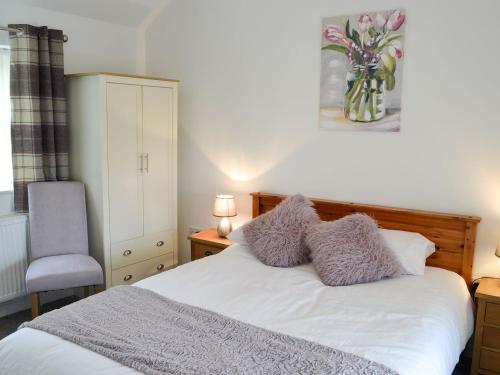 ein Schlafzimmer mit einem Bett mit lila Kissen und einem Stuhl in der Unterkunft Bullions Farm Cottage in Edmondbyers