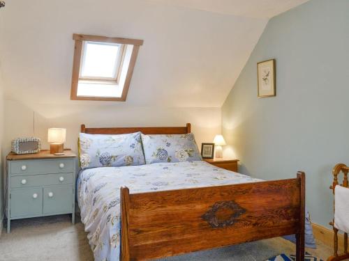 a bedroom with a wooden bed and a window at Larch Cottage in Balnald