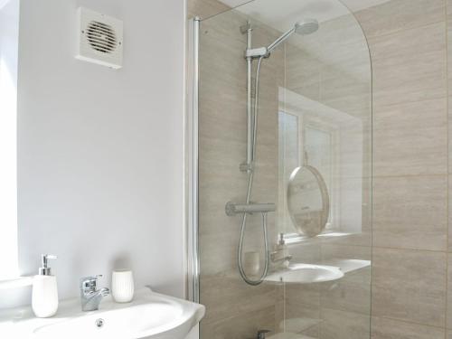 a bathroom with a shower with a sink and a mirror at Hambleton House in Malton