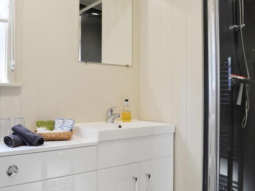 ein weißes Badezimmer mit einem Waschbecken und einem Spiegel in der Unterkunft Curlew in Westward