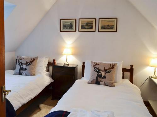 a bedroom with two beds and two lamps on the wall at Coulags Croft in Ross on Wye