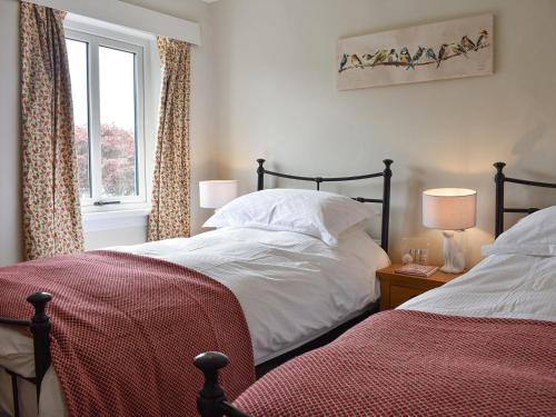 a bedroom with two beds and a window at Finkle Cottage in Pooley Bridge