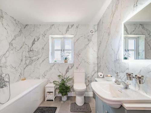 a white bathroom with a tub and a toilet and a sink at Lizzies Cottage in Skendleby