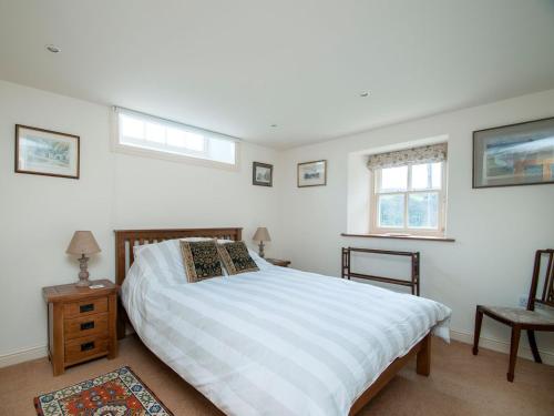 a bedroom with a bed and two windows at The Old Chapel in Gammersgill