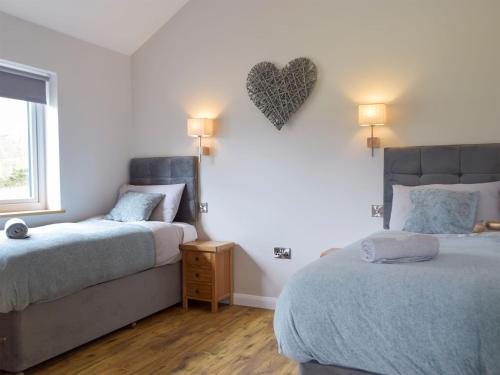 a bedroom with two beds and a heart on the wall at Cadno - Uk32825 in Cwrt-newydd