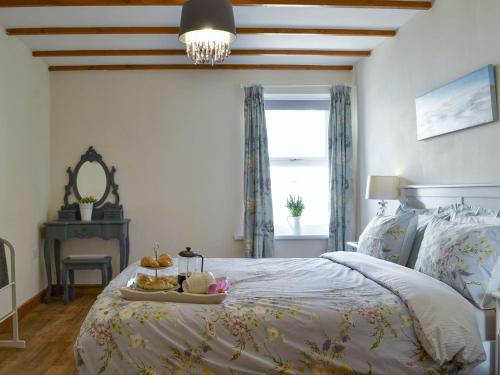 a bedroom with a bed with a tray of food on it at Captains Cottage in Allonby