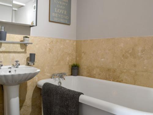 a bathroom with a bath tub and a sink at Captains Cottage in Allonby