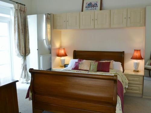 a bedroom with a wooden bed with two lamps on it at Porters Lodge in Axminster