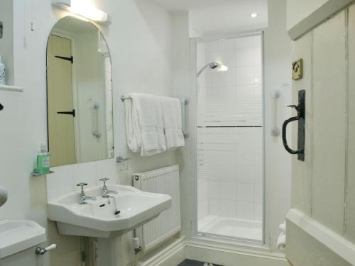 y baño blanco con lavabo y ducha. en Porters Lodge, en Axminster