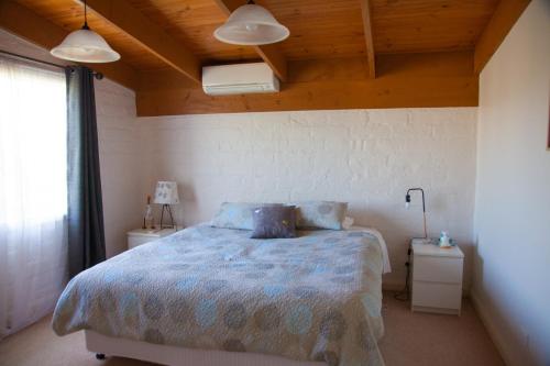 a bedroom with a bed with a blue comforter at Rose Cottage. Cosy, eco-friendly cottage in Yarra Glen. in Yarra Glen