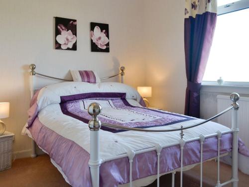 a bedroom with a bed with purple and white sheets at Bel-mar in Whithorn