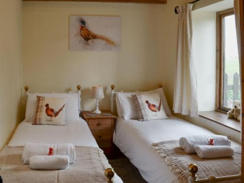 2 camas en un dormitorio con 2 pájaros en las almohadas en Sunflower Holiday Cottage, en Alford