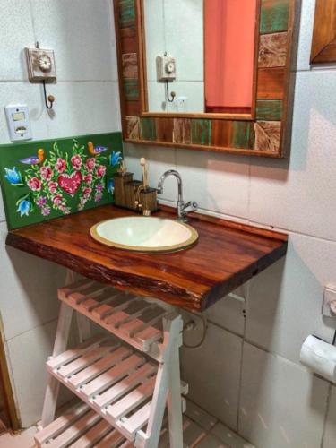 a bathroom with a sink and a mirror at Chalé Bom Jardim in Camanducaia