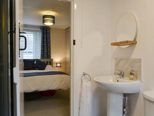 a bathroom with a sink and a bedroom with a bed at Little Nook in St Bees