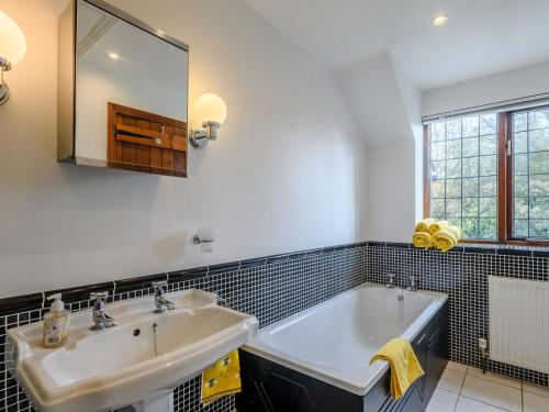 La salle de bains est pourvue d'un lavabo, d'une baignoire et d'un miroir. dans l'établissement The Old Gatehouse, à Heacham