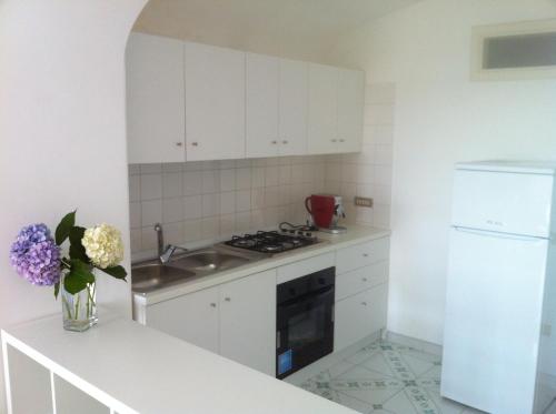 a white kitchen with a sink and a stove at Palazzo Damelio in Scala