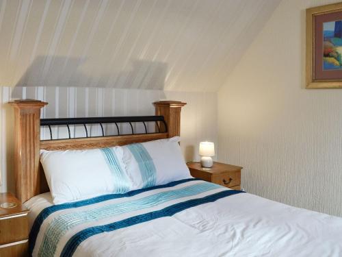 a bedroom with a bed with a wooden headboard at Old Stable Cottage in Uplawmoor
