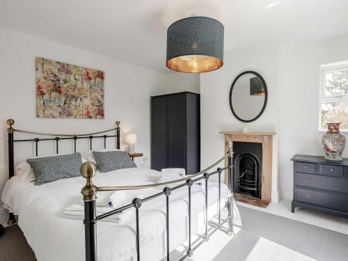 a bedroom with a bed and a mirror and a fireplace at Spinney Cottage in Woodford