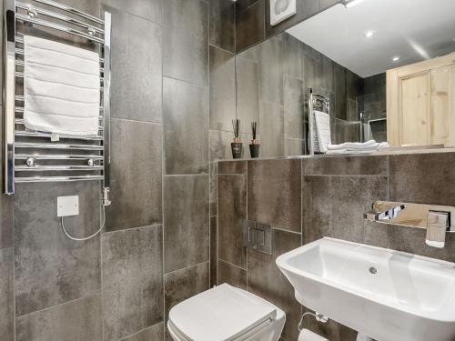 a bathroom with a white toilet and a sink at Spinney Cottage in Woodford