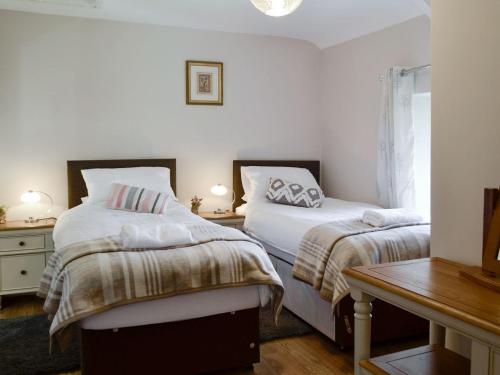 a bedroom with two beds and a wooden table at Brynllefrith Farmhouse in Cymmer