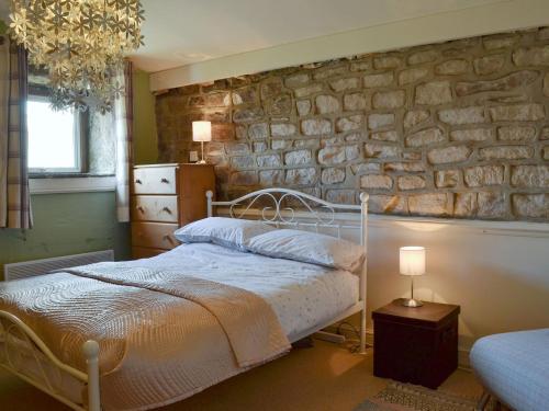 um quarto com uma cama e uma parede de pedra em Halstead Green Farm em Mytholm
