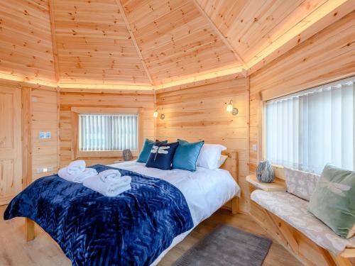 a bedroom with a bed in a wooden cabin at Dragon Fly Retreat-uk36831 in Pentney