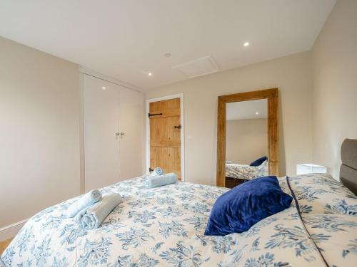 a bedroom with a bed with blue sheets and a mirror at Tyr Ywen Cottage in Abergavenny