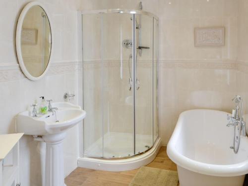 a white bathroom with a shower and a sink at Bay View in Whitley Bay