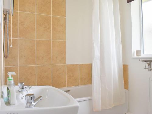 a bathroom with a white sink and a shower at Widgeon Cottage - Uk33873 in Cote