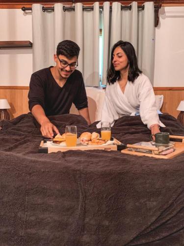 Een man en een vrouw op een bed met borden eten bij Chalé Bom Jardim in Camanducaia