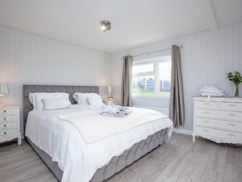 a white bedroom with a large bed and a window at Lookout Lodge-uk36700 in Newton Abbot
