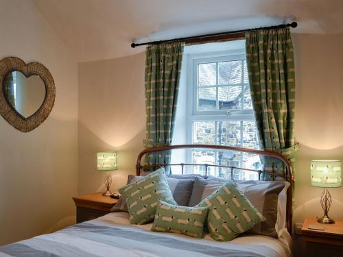a bedroom with a bed with green curtains and a window at Noddfa Cottage in Llanfair Talhaiarn
