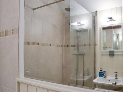 a shower with a glass door next to a sink at Noddfa Cottage in Llanfair Talhaiarn