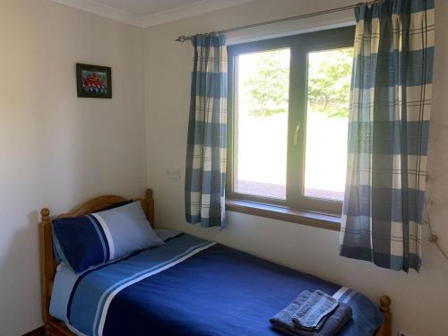 ein kleines Schlafzimmer mit einem Bett und einem Fenster in der Unterkunft Harelaw Brae in Grantshouse