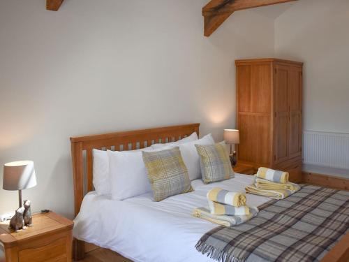 1 dormitorio con 1 cama con sábanas y almohadas blancas en Stabal Eithinog en Pen-y-groes