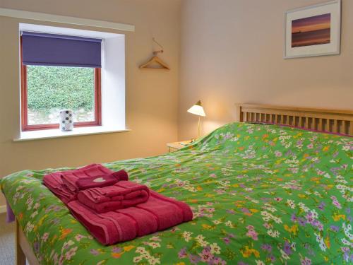 a bedroom with a bed with a red blanket and a window at Ashfield in Paxton