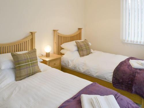 Horsley的住宿－North Farm Bungalow，一间卧室设有两张床和一张桌子上的台灯。
