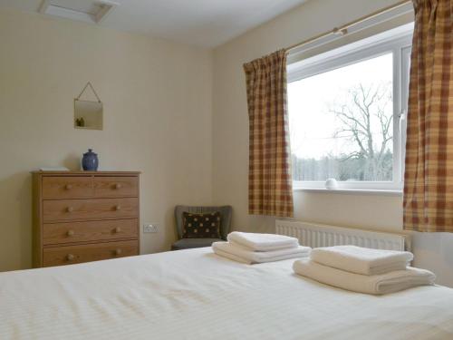 a bedroom with a bed with three towels on it at Holly Cottage in Cockermouth