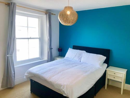 a blue bedroom with a bed and a window at Summerland Terrace in Kingswear