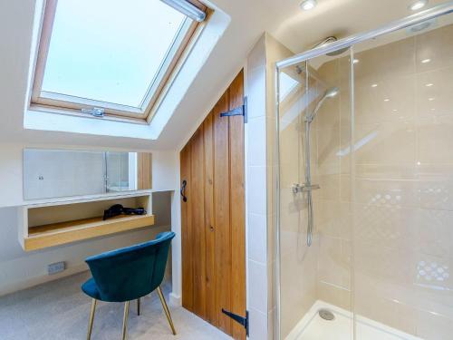 a bathroom with a glass shower and a blue chair at Woodpecker Cottage in Inglewhite