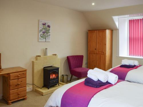 a bedroom with two beds and a wood stove at The Dairy House in Creebridge