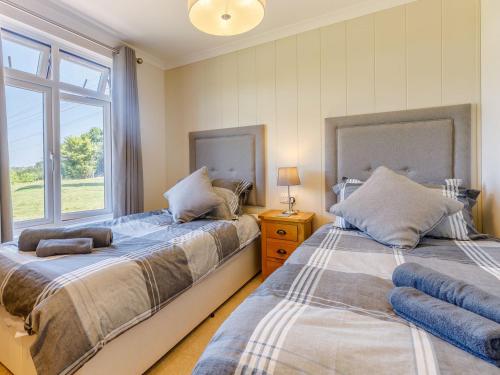 two beds in a room with a window at Nanny Goat Lodge in Crossway Green