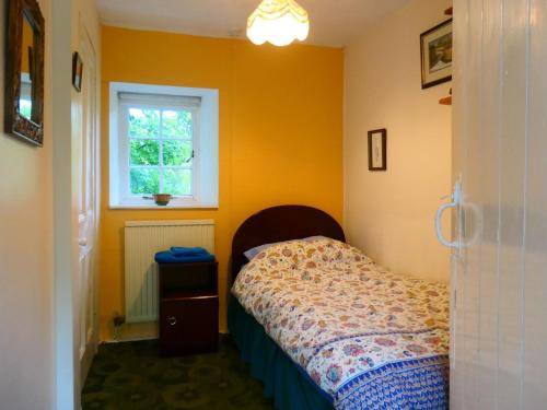 niewielka sypialnia z łóżkiem i oknem w obiekcie Bridge Cottage w mieście Lockerbie