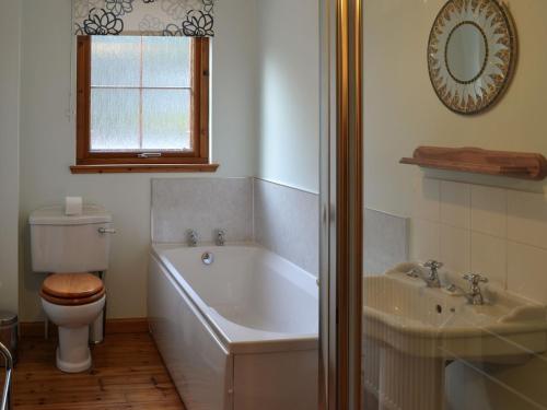 a bathroom with a tub and a toilet and a sink at Woodland Lodge in Boat of Garten