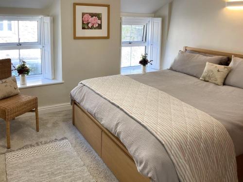 una camera con un letto e una sedia e due finestre di Towd Mans Cottage a Bonsall