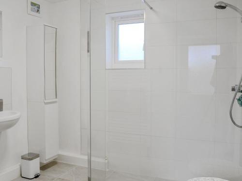 a white bathroom with a shower and a sink at Katellen Cottage in Threlkeld