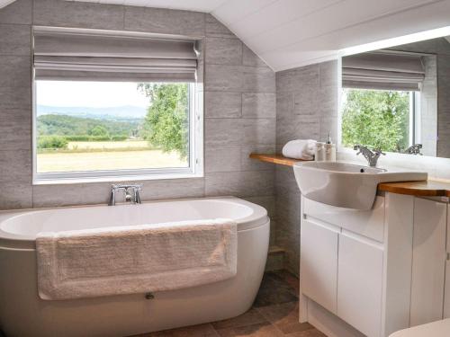 a bathroom with a tub and a sink and a window at Beacon Cottage in Ivegill