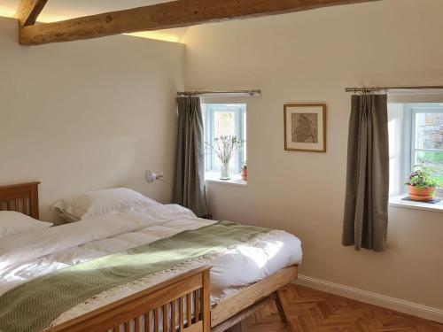 a bedroom with a bed and two windows at Dowie House Steading in Cheswick